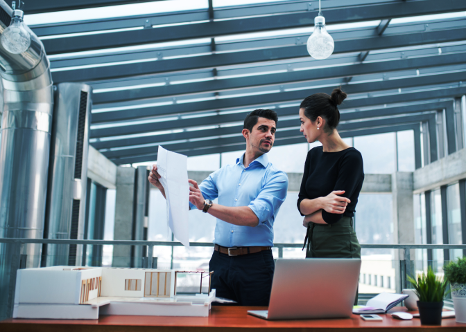 Two designers in an open office looking at paper